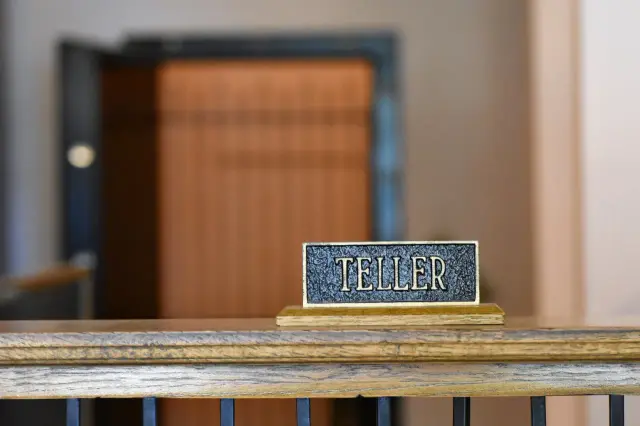 A bank teller window with a brass TELLER sign